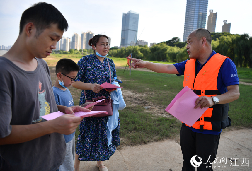 救援隊(duì)隊(duì)員正在贛江邊向市民發(fā)放防溺水宣傳資料。 人民網(wǎng) 時(shí)雨攝