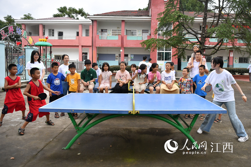 支教學生和留守兒童們在簡易球桌上一起打乒乓球。 人民網(wǎng) 時雨攝