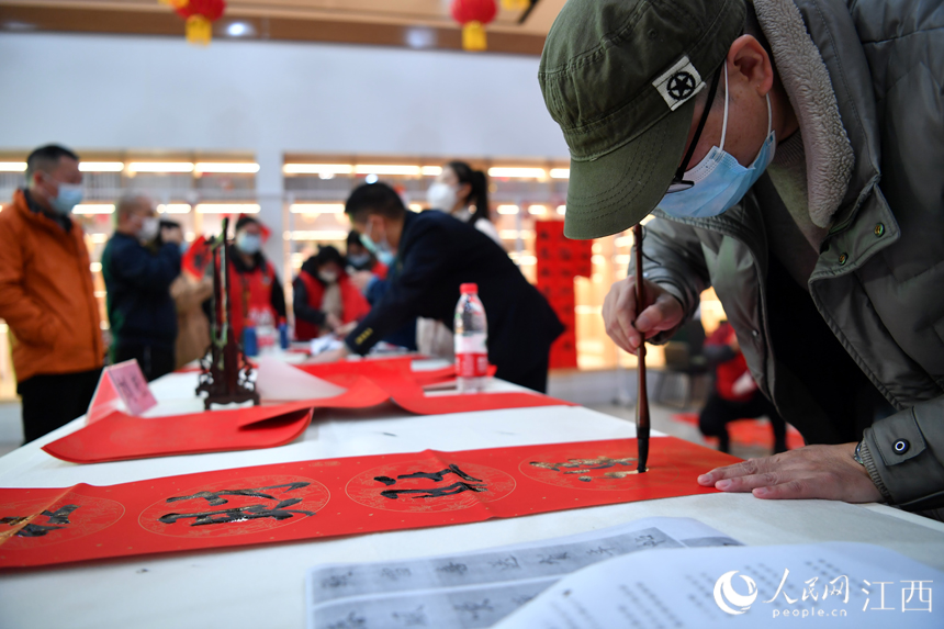 春運(yùn)首日，書(shū)法愛(ài)好者在候車大廳寫(xiě)春聯(lián)，并免費(fèi)贈(zèng)給旅客。人民網(wǎng) 時(shí)雨攝