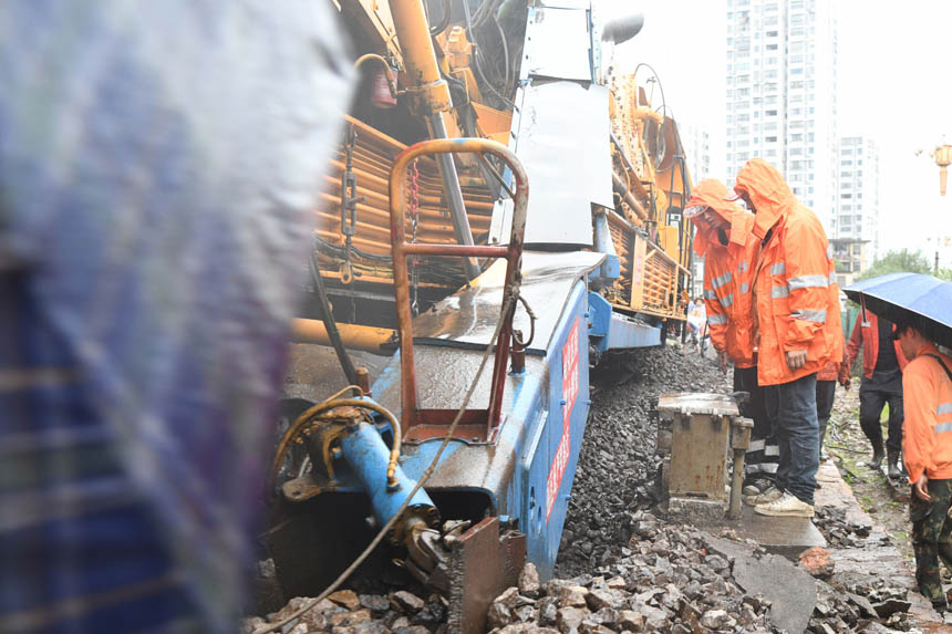 中國鐵路南昌局集團(tuán)有限公司福州電務(wù)段職工在雨中盯控大機(jī)清篩旁的信號(hào)設(shè)備。姜振濤攝