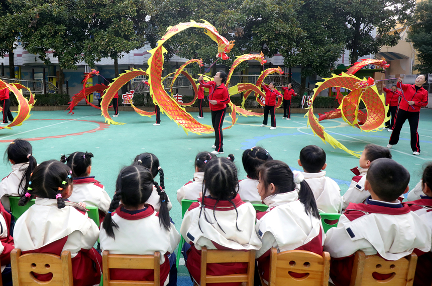 在宜豐縣新昌大道旁的宜豐幼兒園，孩子們觀看“彩帶龍”表演。何賤來攝