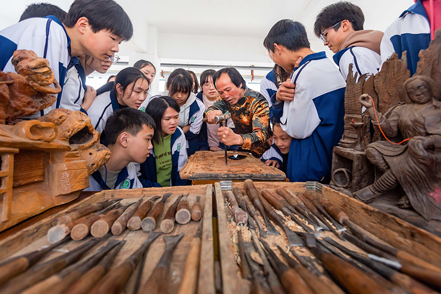 當(dāng)?shù)氐窨碳寄艽髱熢诮o孩子們講解雕刻技藝。王惠民攝