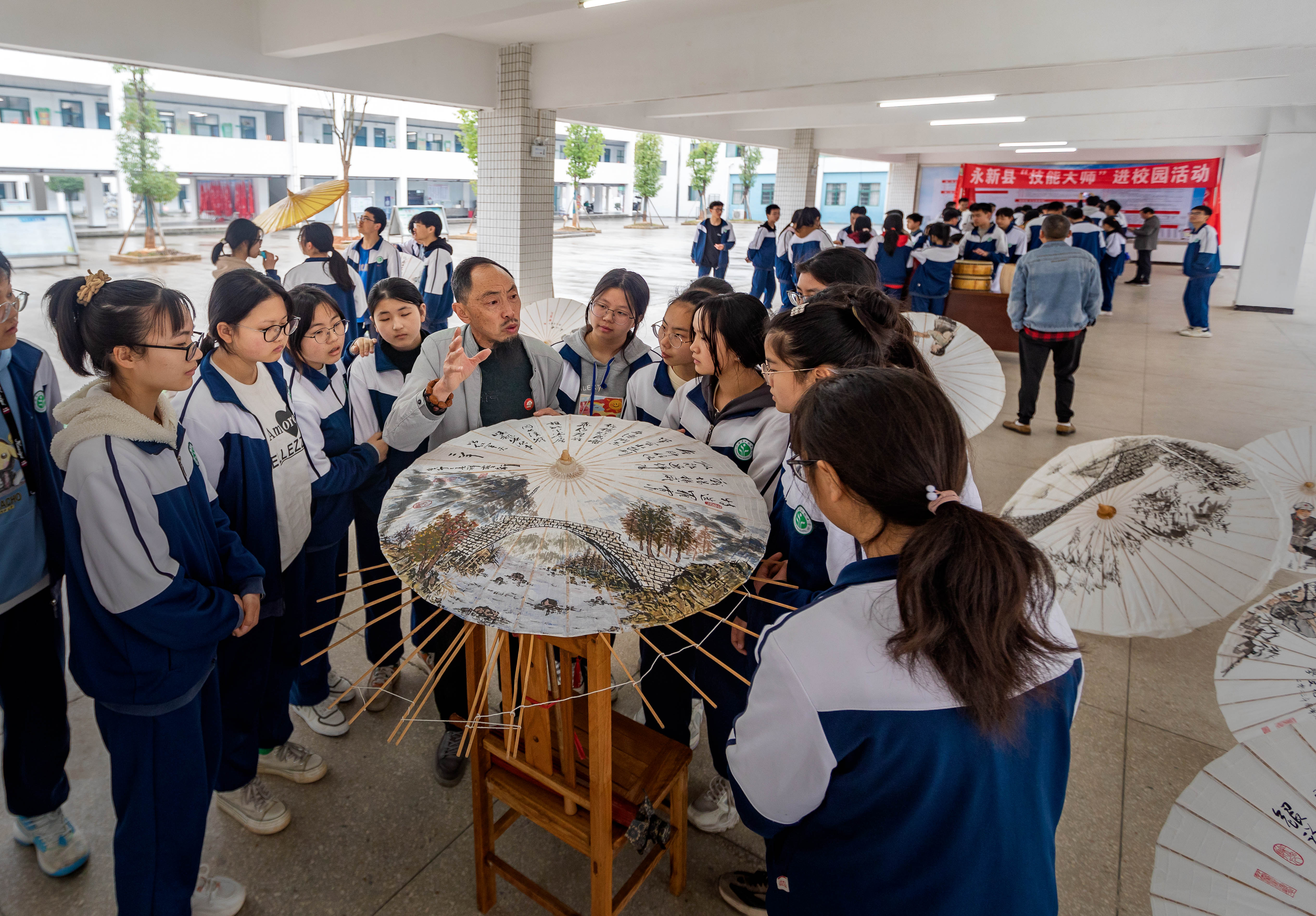 當(dāng)?shù)赜图垈阒谱骷寄艽髱熢谙蚝⒆觽冎v解油紙傘的制作技藝。王惠民攝