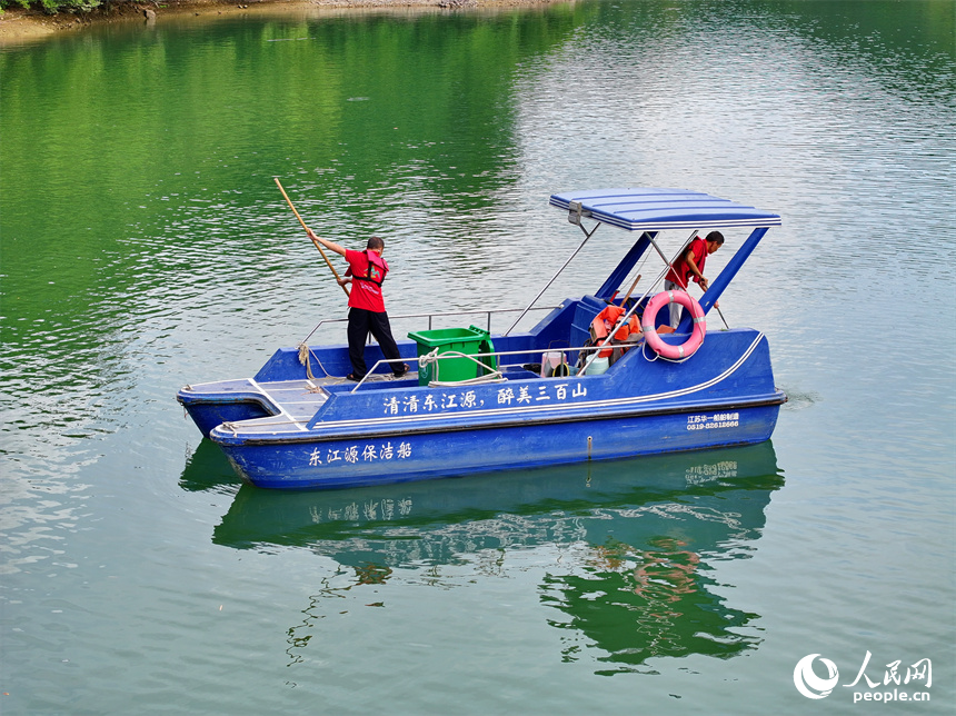 近日，江西省贛州市安遠(yuǎn)縣三百山東風(fēng)湖，生態(tài)保潔員駕駛保潔船在清理水面漂浮物。人民網(wǎng) 朱海鵬攝