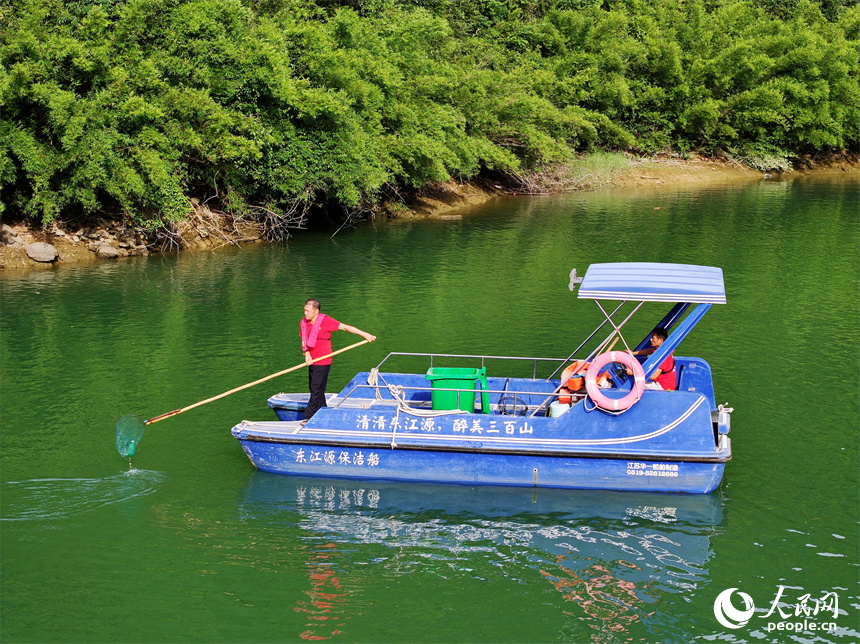 近日，江西省贛州市安遠(yuǎn)縣三百山東風(fēng)湖，生態(tài)保潔員駕駛保潔船在清理水面漂浮物。人民網(wǎng) 朱海鵬攝