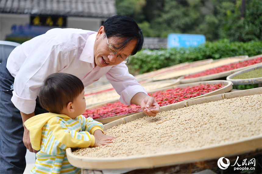 一位游客正在教孩子識別曬匾中的農(nóng)作物。 人民網(wǎng)記者 時雨攝